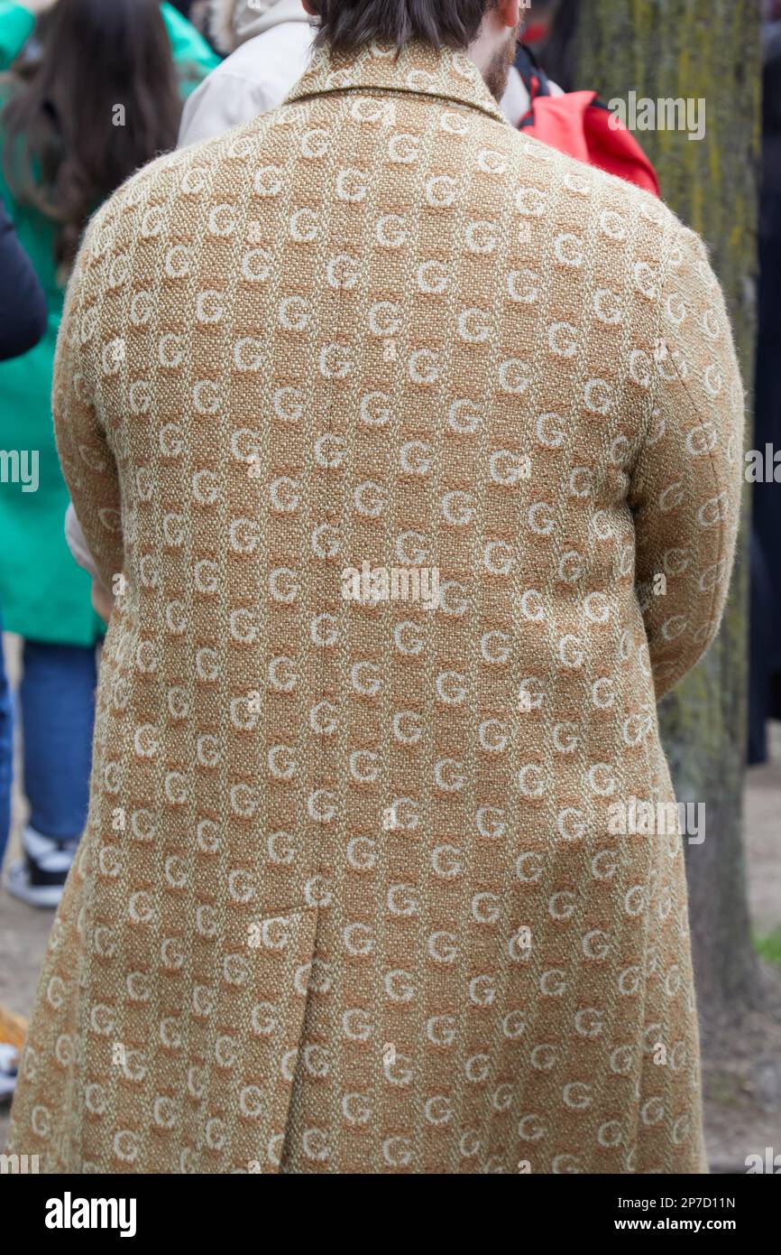 MILÁN, ITALIA - 22 DE FEBRERO de 2023: Hombre con abrigo de patrón G marrón antes del desfile de Fendi, estilo callejero de la Semana de la Moda de Milán Foto de stock