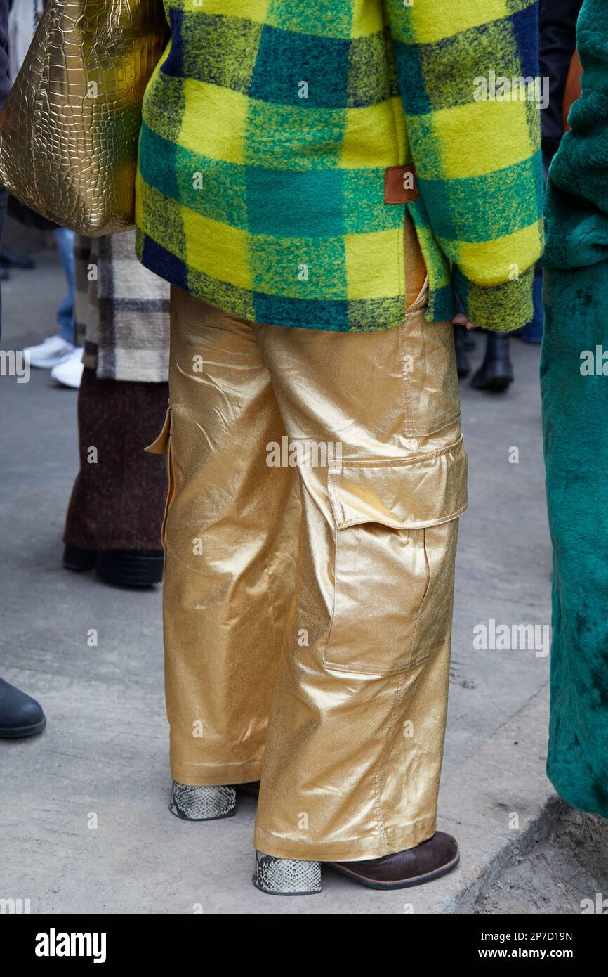 MILÁN, ITALIA - 22 DE FEBRERO de 2023: Mujer con pantalón cargo dorado y chaqueta a cuadros amarilla y verde antes del desfile de Fendi, Milan Fashion Week Foto de stock