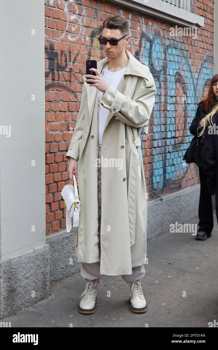 MILÁN, ITALIA - 22 DE FEBRERO de 2023: Hombre con gabardina beige y bolso Fendi de piel blanca antes del desfile de Fendi, estilo urbano de la Semana de la Moda de Milán Foto de stock