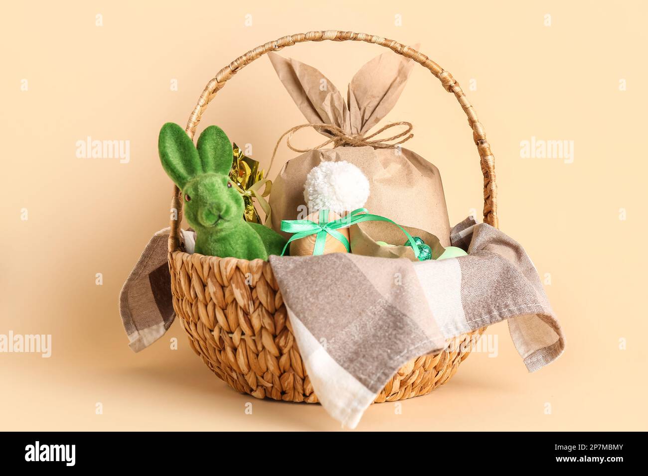 Cesta con conejito, huevos de Pascua y bolsa de regalo sobre fondo beige  Fotografía de stock - Alamy