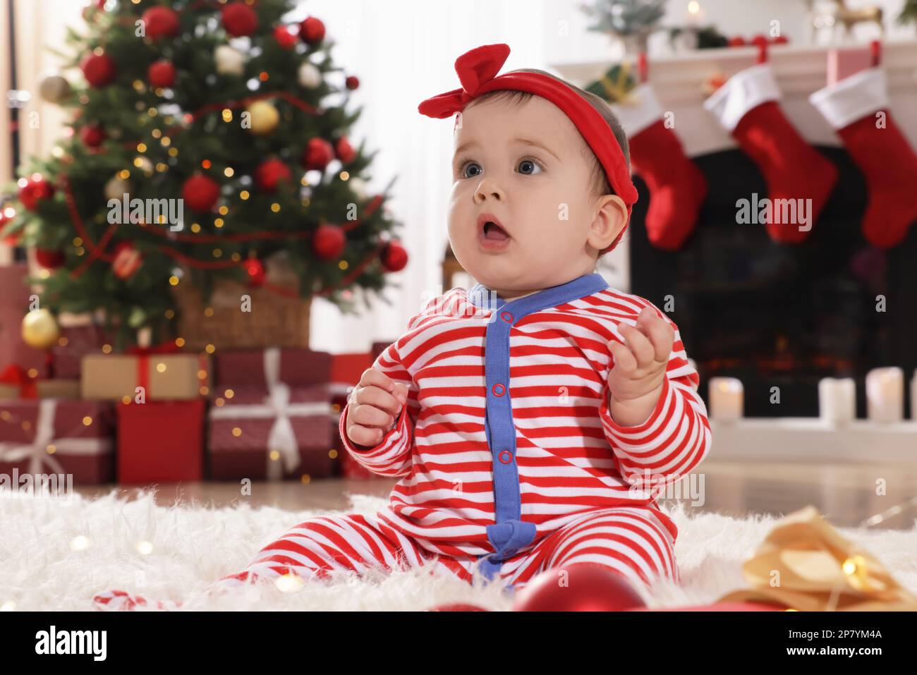 Bebé con pijama de Navidad brillante en el piso en la habitación Fotografía  de stock - Alamy