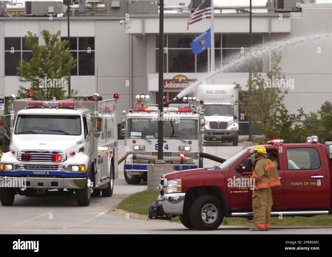 Emergency personnel stage near a retention pond as they work at a fire