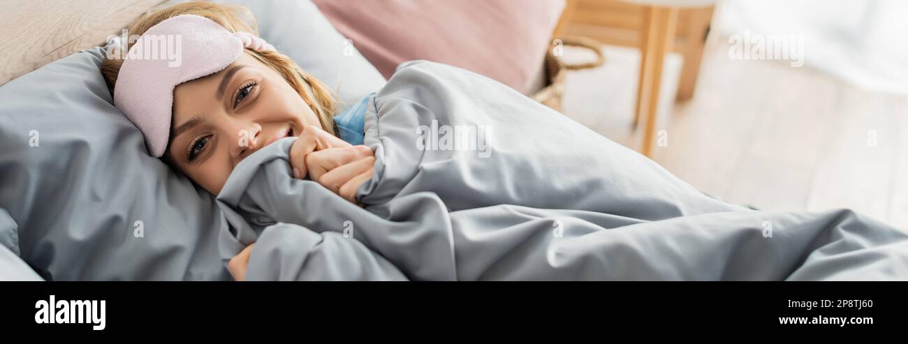 mujer joven feliz en la máscara de dormir que miente debajo de la manta en  la cama cómoda, bandera, imagen de stock Fotografía de stock - Alamy