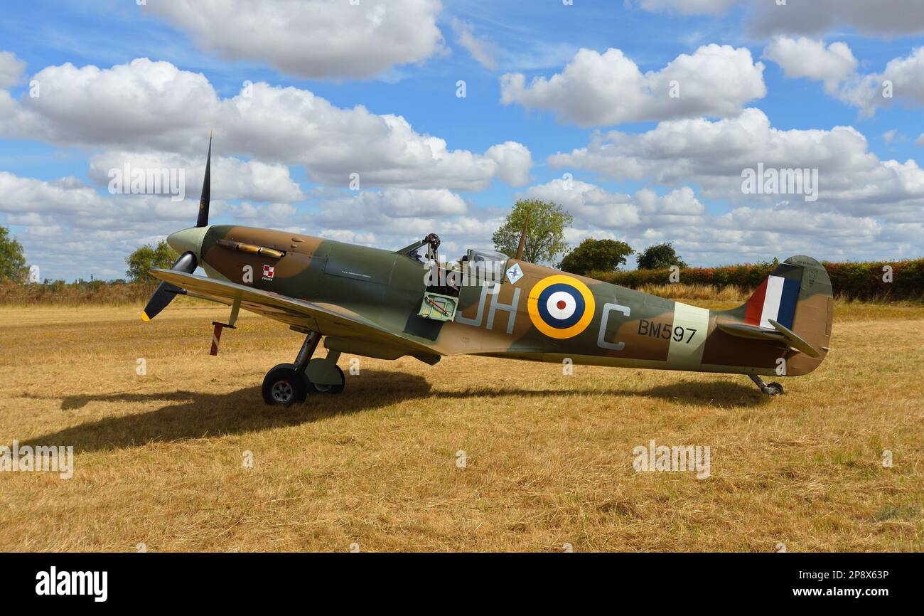 LITTLE GRANSDEN, CAMBRIDGESHIRE, INGLATERRA - 28 DE AGOSTO de 2022: Vintage Spitfire BM597 (G-MKVB) Mk.Vb estático en pista de aterrizaje con cielo azul y nubes. Foto de stock
