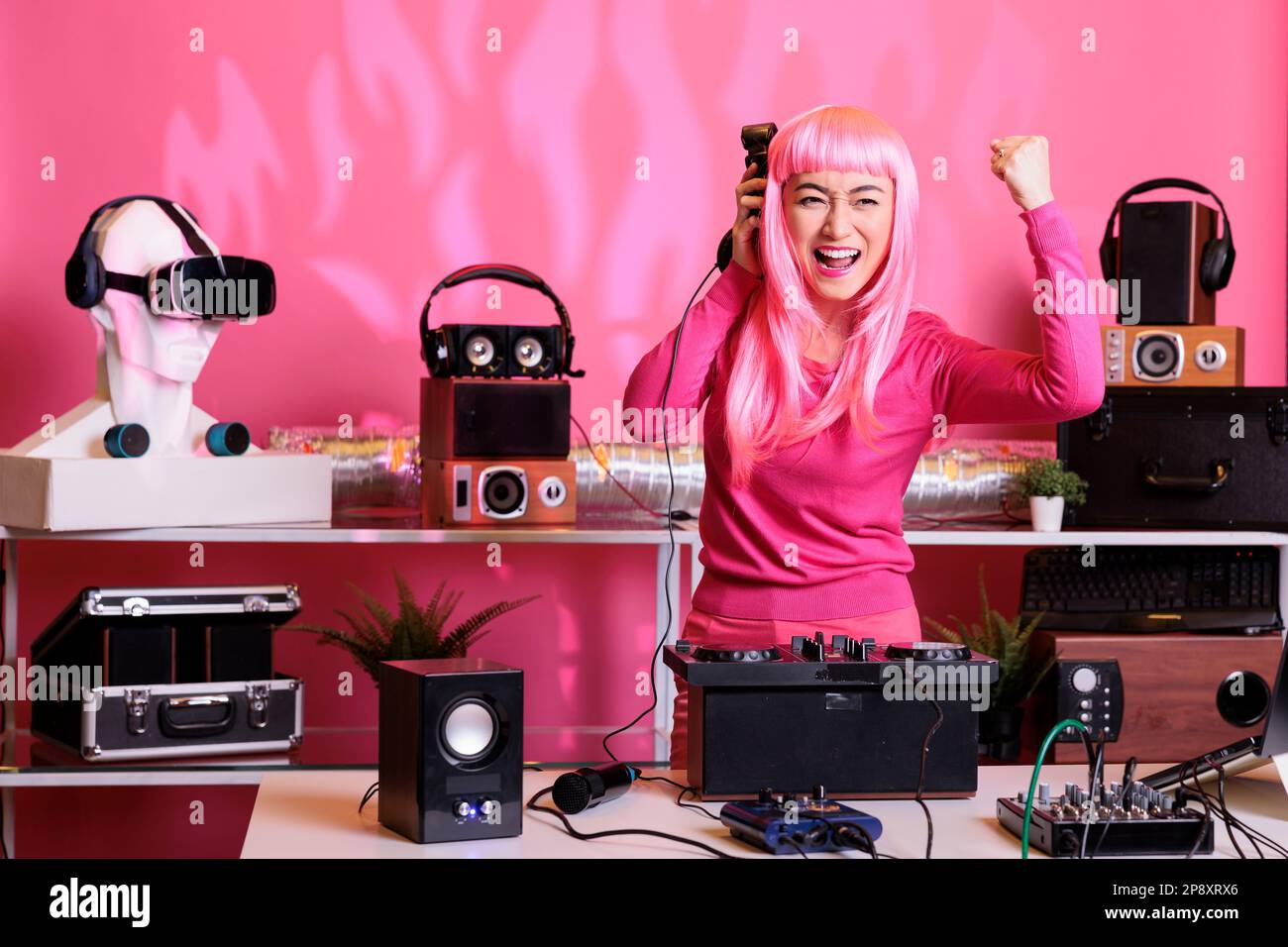 dj asiático con cabello rosa mezclando música techno con eletronic  divirtiéndose en el club durante la noche, interpretando canciones usando  tocadiscos profesionales. Artista celebrando el álbum con los fans en el  estudio