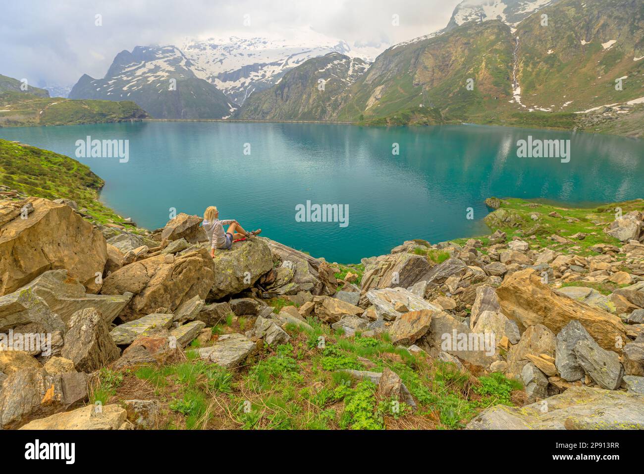 Chica deportiva descansando durante el trekking alrededor del lago Robiei de Suiza. Embalse suizo en el valle de Maggia del cantón del Tesino con la presa de Robiei. Parte superior Foto de stock
