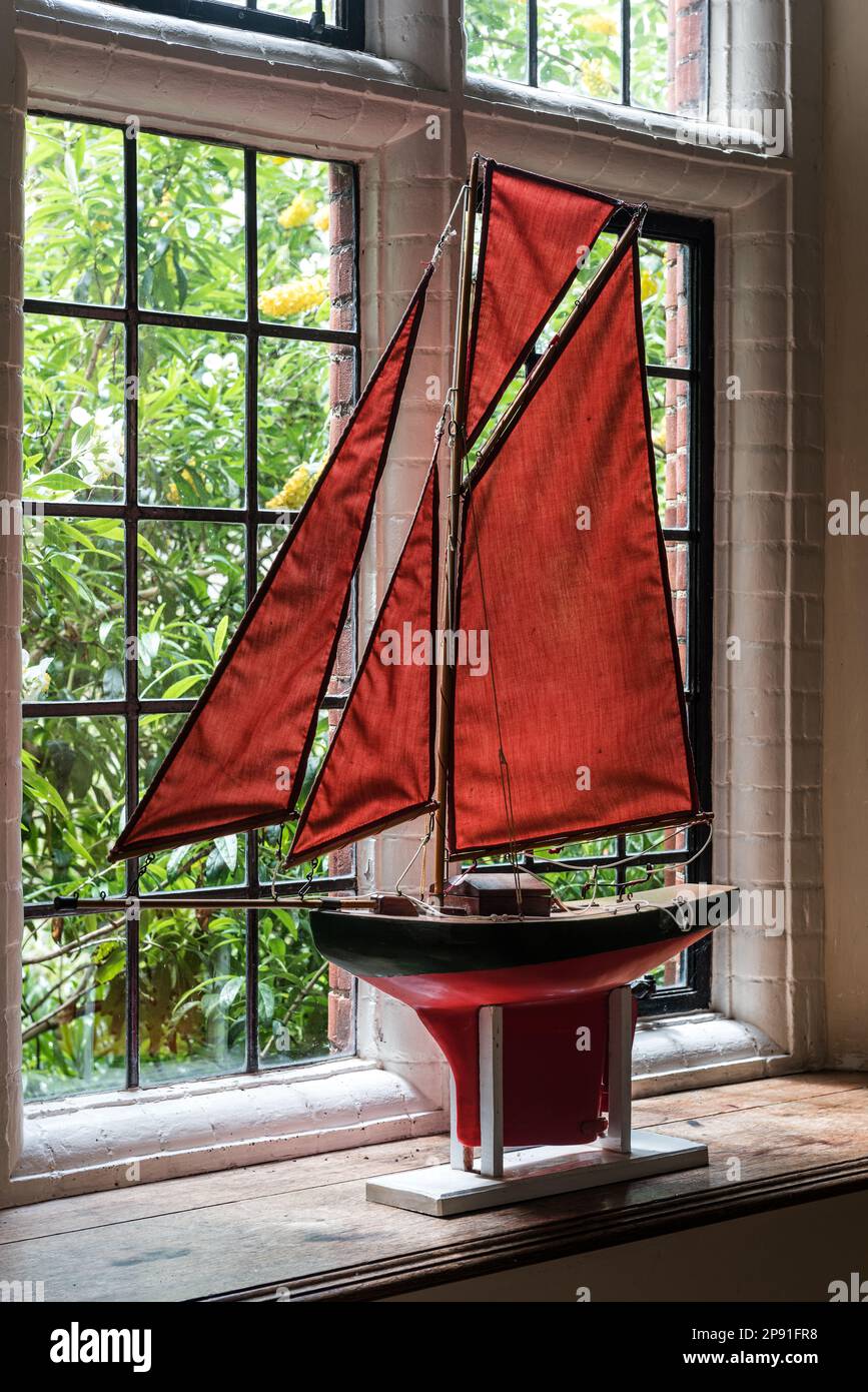 Barco modelo con velas rojas en la ventana de Wiveton Hall, una casa señorial jacobea del siglo 17th en Norfolk, Reino Unido Foto de stock