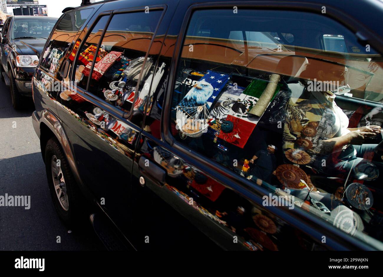 Merchandise for sale is reflected in the window of a car waiting in