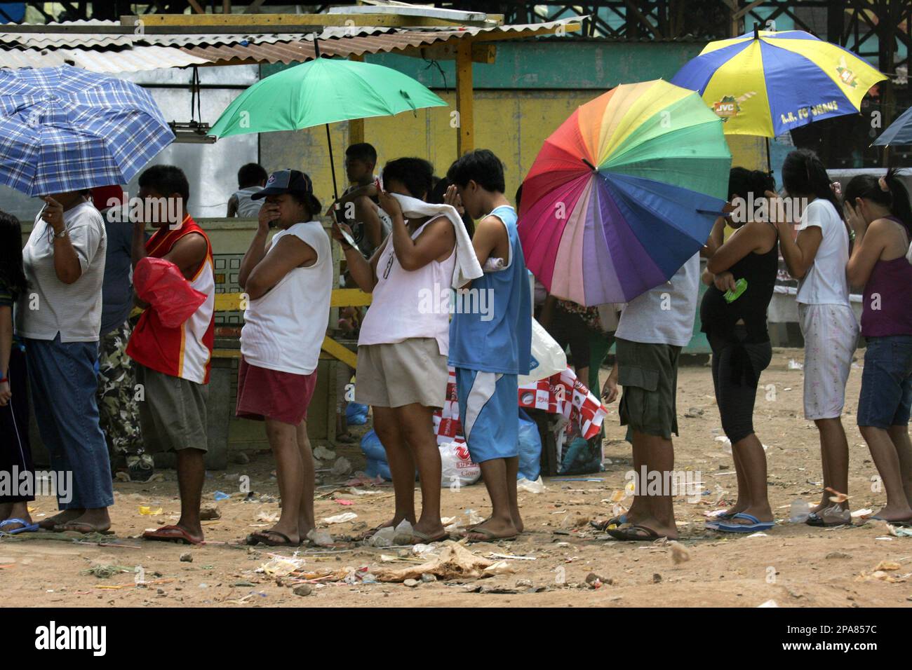 Residents protect themselves from the dust as they queue up to buy the