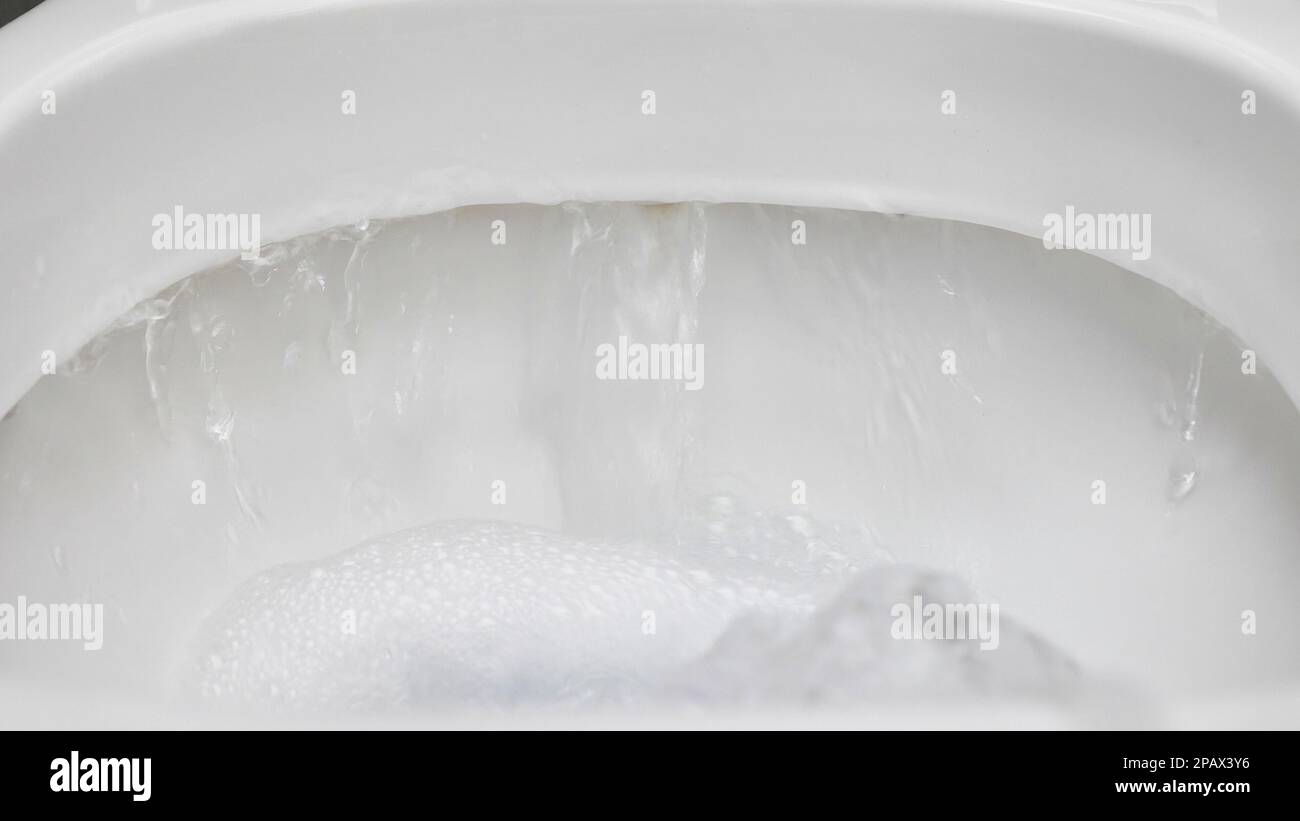 Ducha higiénica en la mano con un chorro de agua, de cerca en un inodoro  blanco Fotografía de stock - Alamy