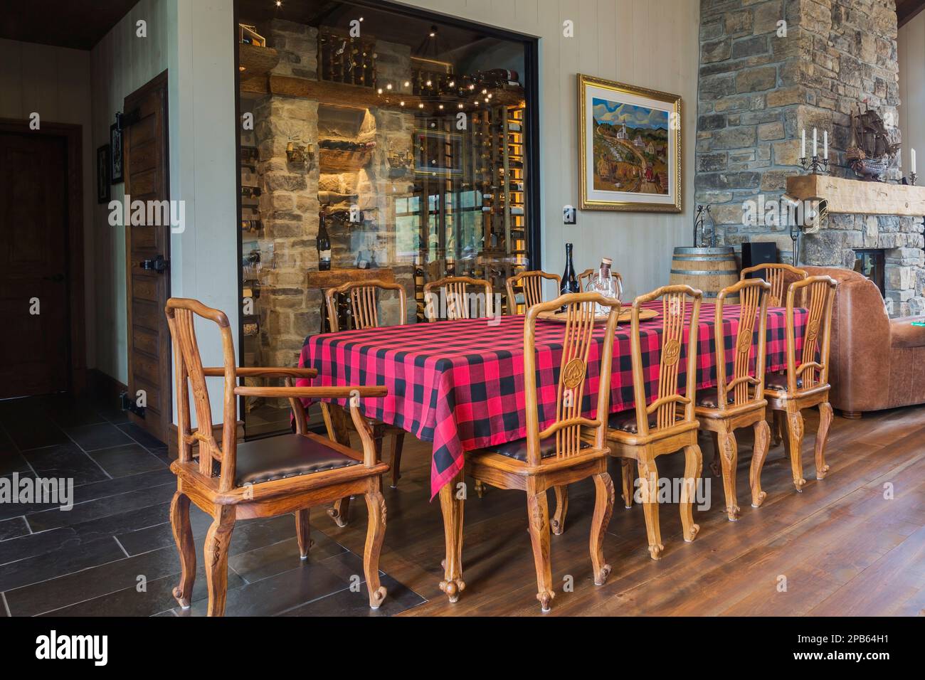 Mesa de teca con sillas de respaldo alto y pisos de madera de pino rojo manchados en el comedor dentro de la casa con estructura de madera híbrida. Foto de stock