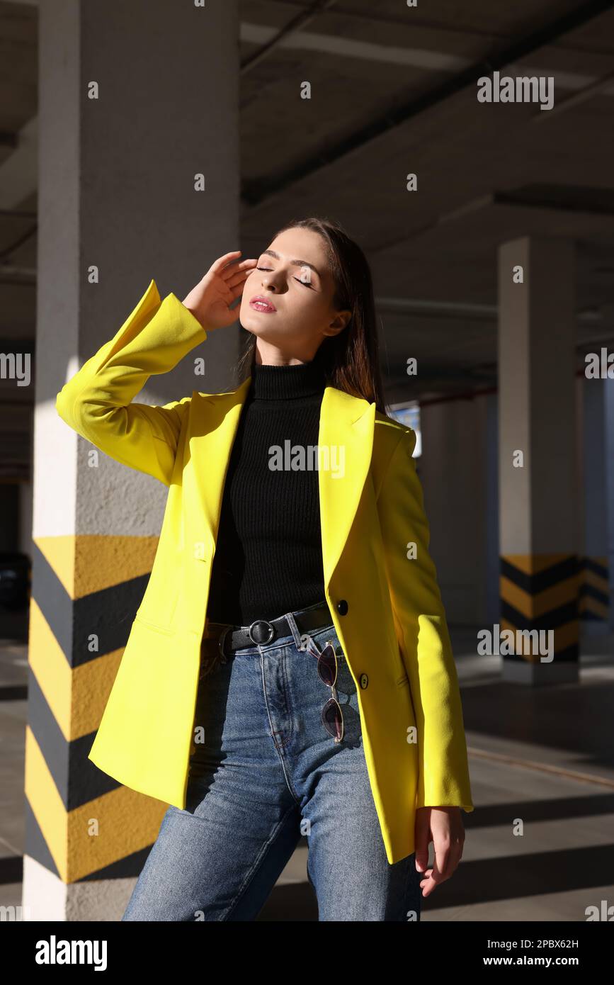 Mujer joven de moda que lleva traje elegante con la chaqueta amarilla en el  garaje de estacionamiento abierto Fotografía de stock - Alamy