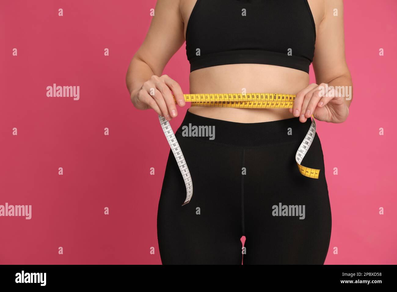 Mujer que mide la cintura con cinta sobre fondo rosa, closeup. Espacio para  texto Fotografía de stock - Alamy