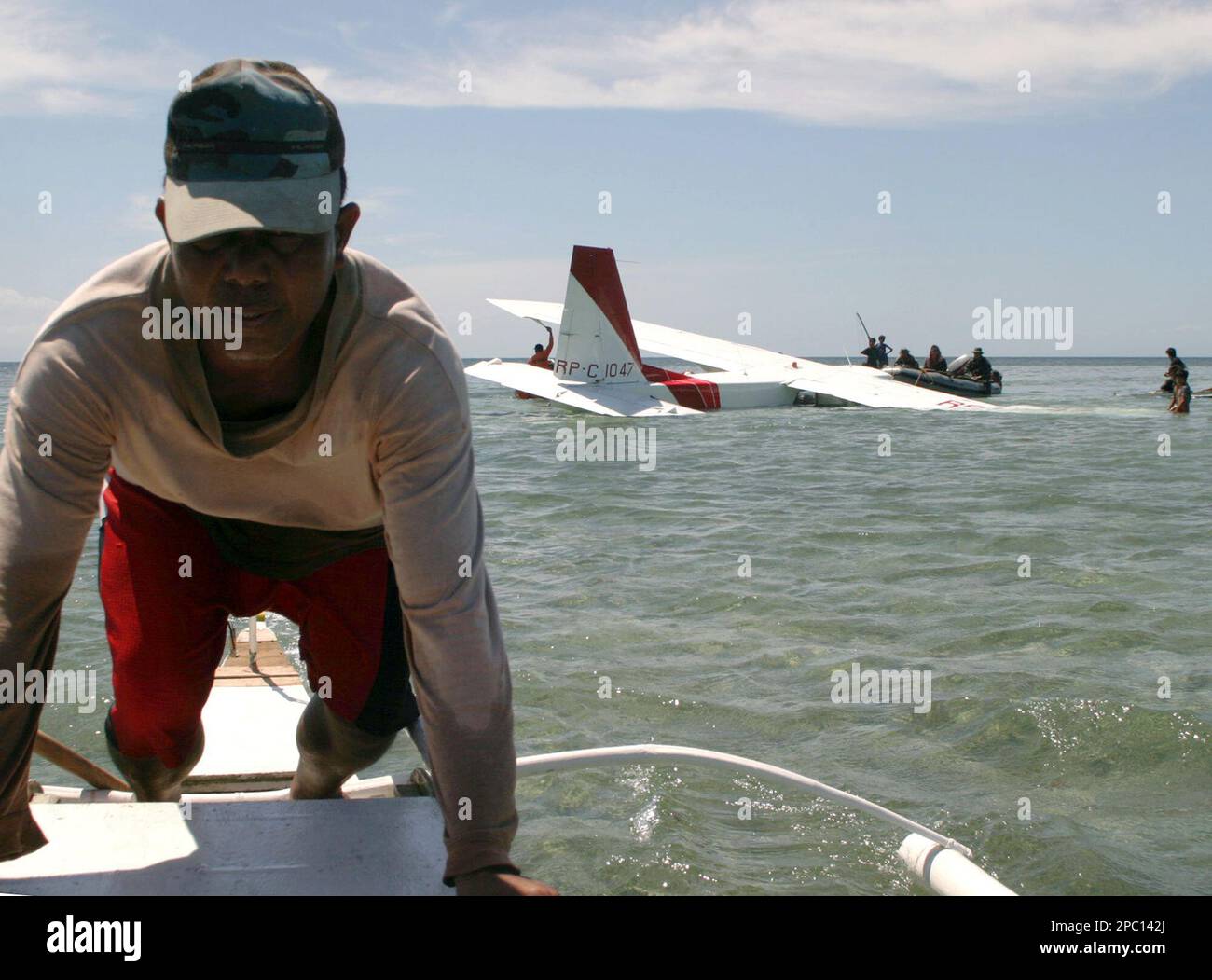 A Filipino fisherman maneuvers his boat near a twinengine BritainNorman Islander aircraft