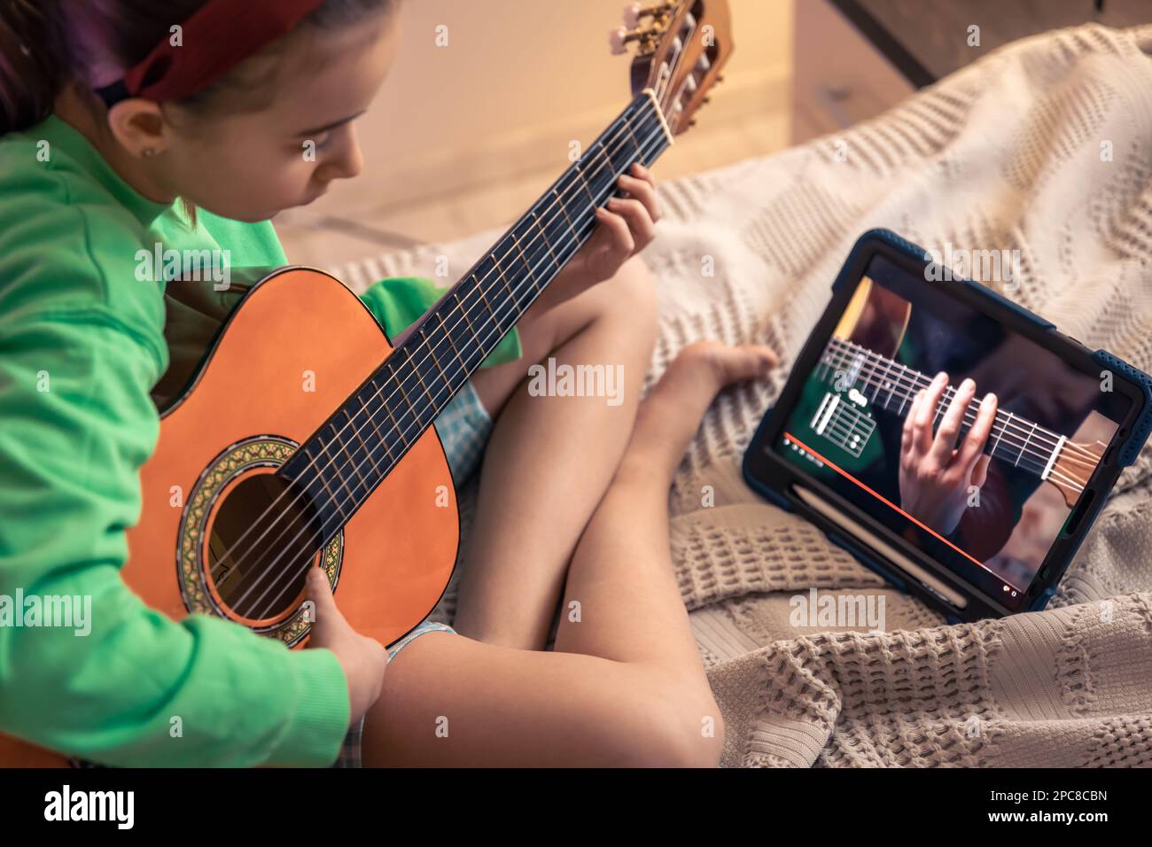 La niña aprende a tocar la guitarra, lección de video de música en línea  Fotografía de stock - Alamy