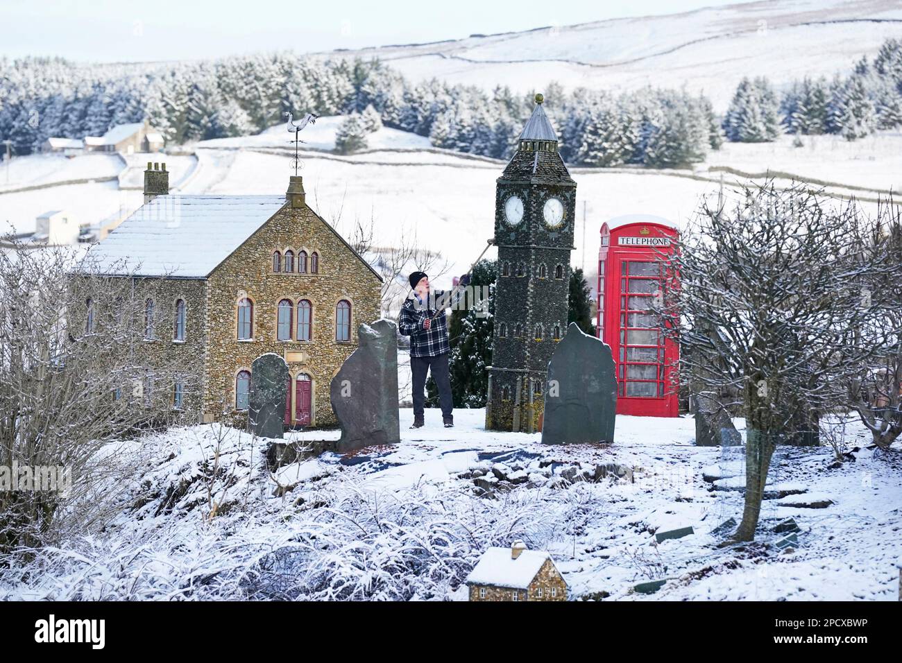 Lawson Robinson, de 77 años, limpia la nieve de su aldea modelo que construyó en su jardín para recaudar dinero para caridad, en Nenthead, en Cumbria. Fecha de la fotografía: Martes 14 de marzo de 2023. Foto de stock