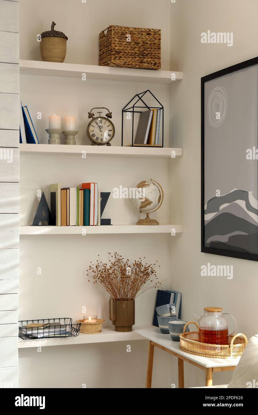 Libros, despertador y decoración diferente en los estantes de la  habitación. Diseño de interiores Fotografía de stock - Alamy
