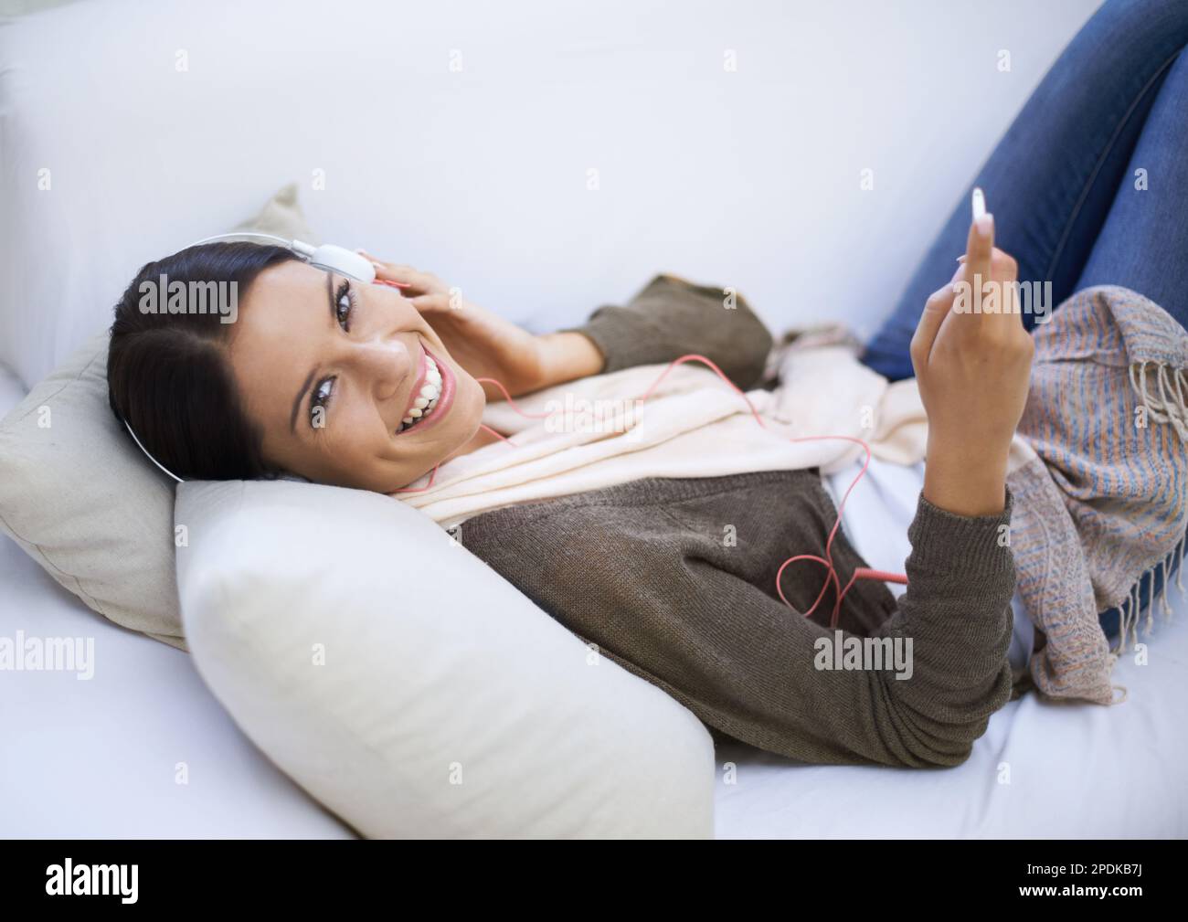 Ella ama su música. Retrato de una mujer joven atractiva que escucha a su  reproductor de mp3 mientras está acostado en el sofá Fotografía de stock -  Alamy
