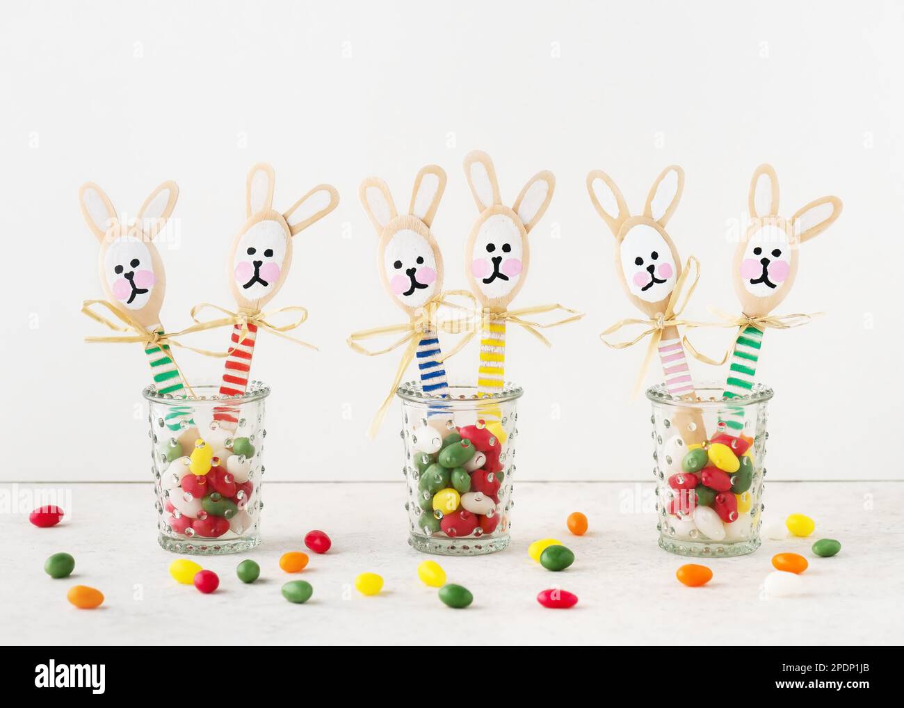 Conejitos coloridos hechos a mano hechos de cucharas de madera en vasos con  huevos dulces de caramelo. Pequeño regalo o decoración para Pascua. Fácil  diversión niños manualidades concepto Fotografía de stock -