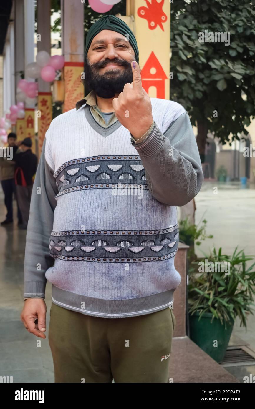 Nueva DELHI, INDIA - 04 2022 de diciembre - Personas no identificadas mostrando sus dedos marcados con tinta después de emitir votos frente a la cabina de votación del este de Delhi Foto de stock