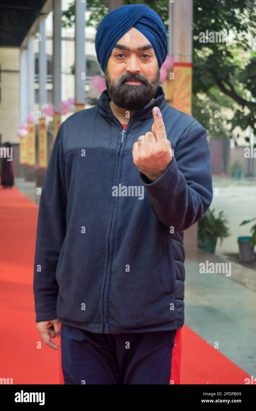 Nueva DELHI, INDIA - 04 2022 de diciembre - Personas no identificadas mostrando sus dedos marcados con tinta después de emitir votos frente a la cabina de votación del este de Delhi Foto de stock