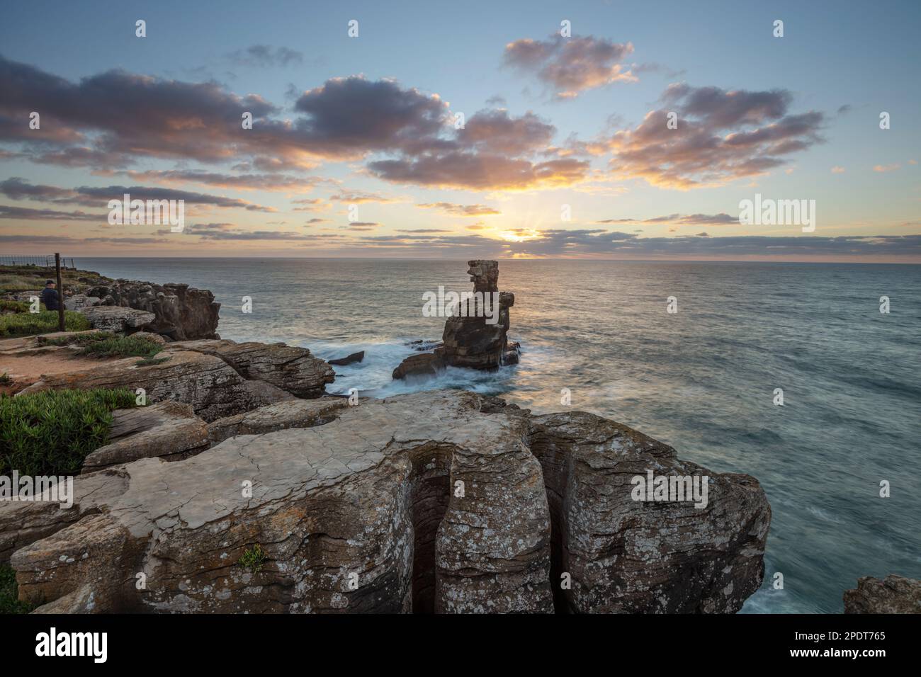 Puesta de sol detrás de la pila de roca en Cabo Carvoeiro con el mar tormentoso, Peniche, Región Central, Portugal, Europa Foto de stock