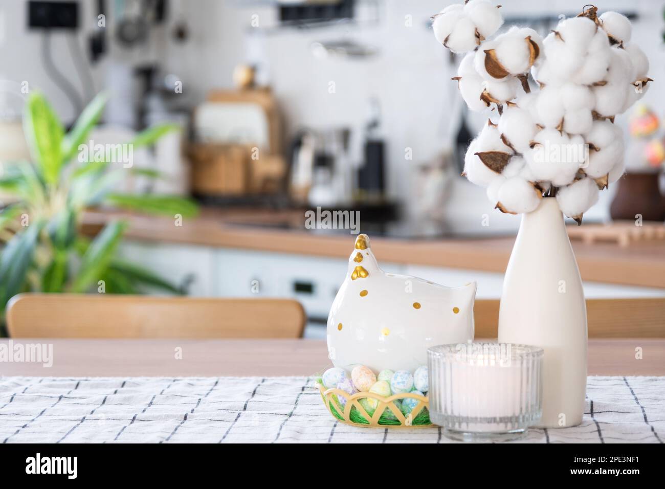 Decoración de Pascua de huevos de colores en una cesta y un pollo en la mesa de la cocina en un estilo rústico. Interior festivo de una casa de campo Foto de stock