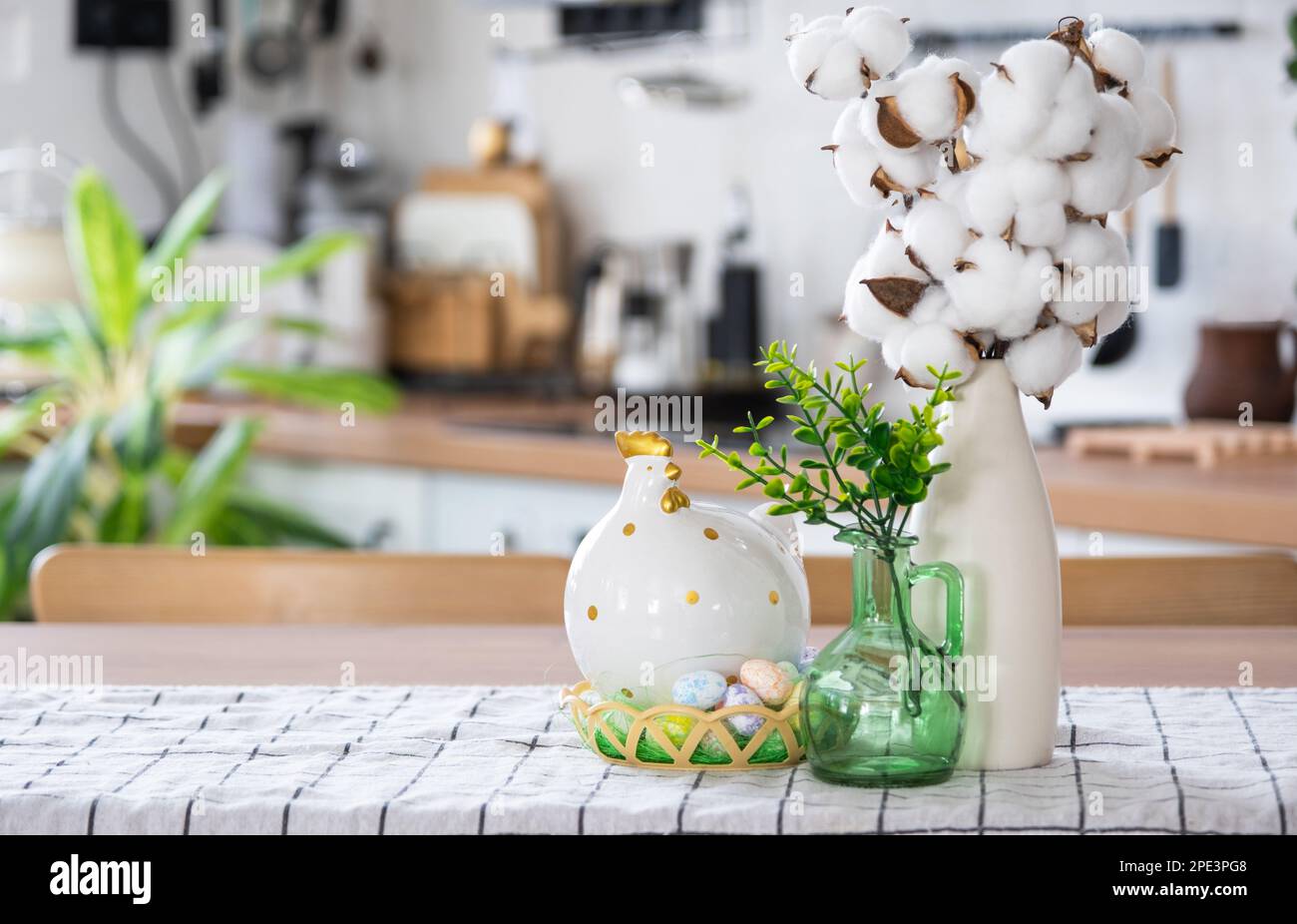 Decoración de Pascua de huevos de colores en una cesta y un pollo en la mesa de la cocina en un estilo rústico. Interior festivo de una casa de campo Foto de stock