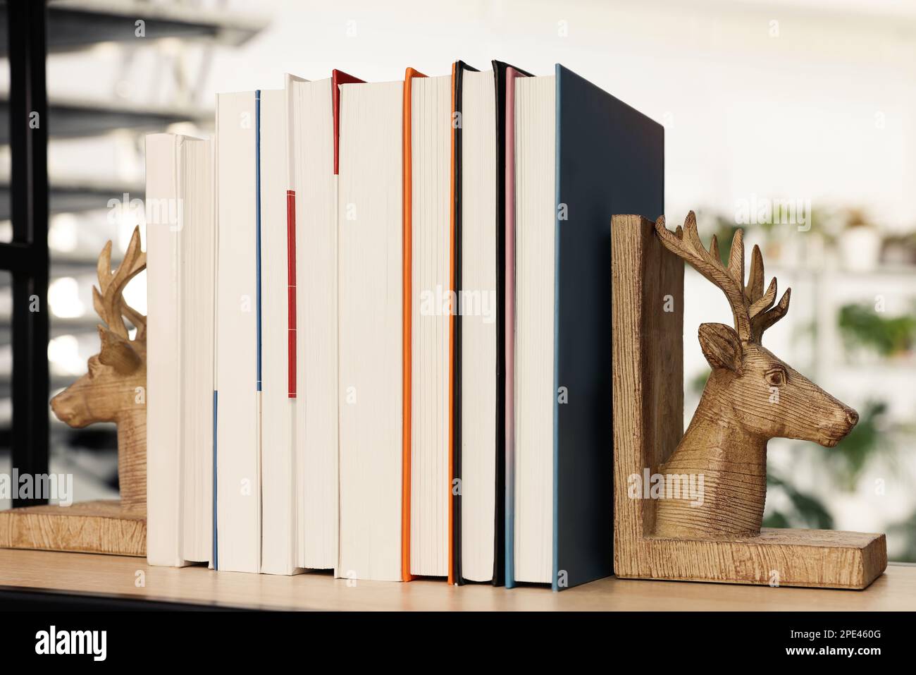 Sujetaleros en forma de ciervo de madera con libros en el estante interior Foto de stock