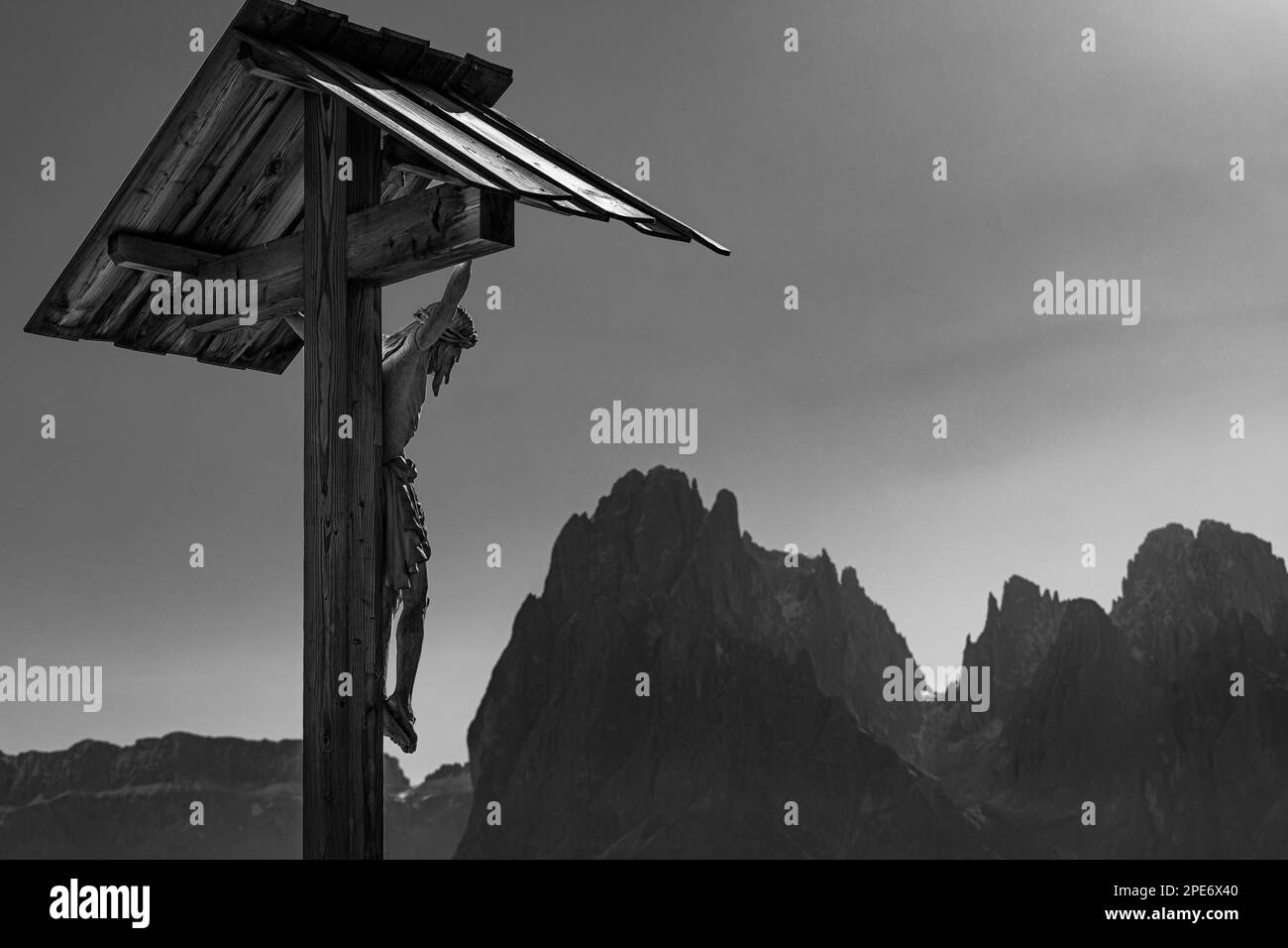 Cruz tallada, detrás de los picos del grupo Sassolungo, foto en blanco y negro, Alpe di Siusi, Val Gardena, Dolomitas, Tirol del Sur, Italia Foto de stock