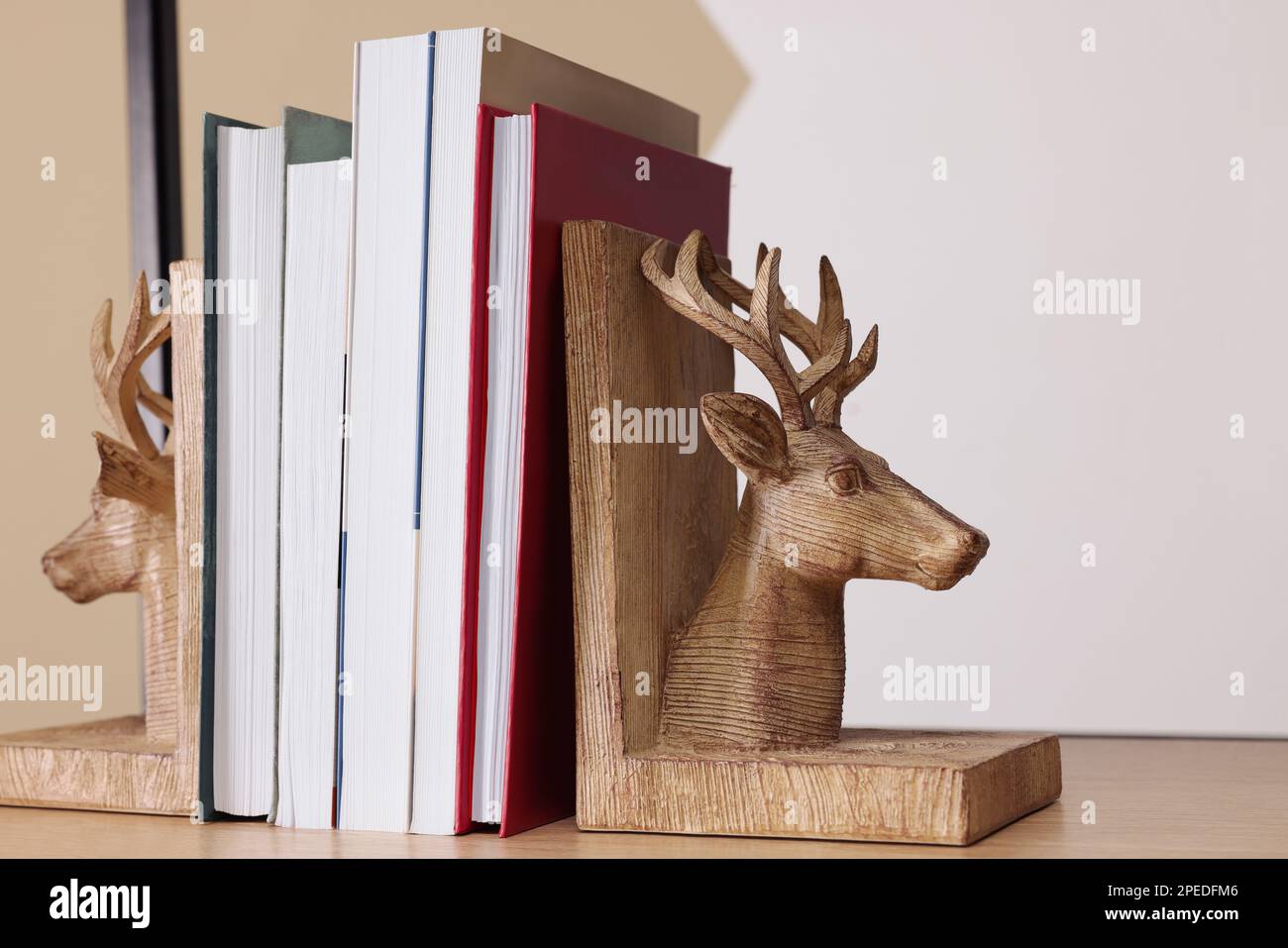 Sujetaleros en forma de ciervo de madera con libros en el estante interior Foto de stock