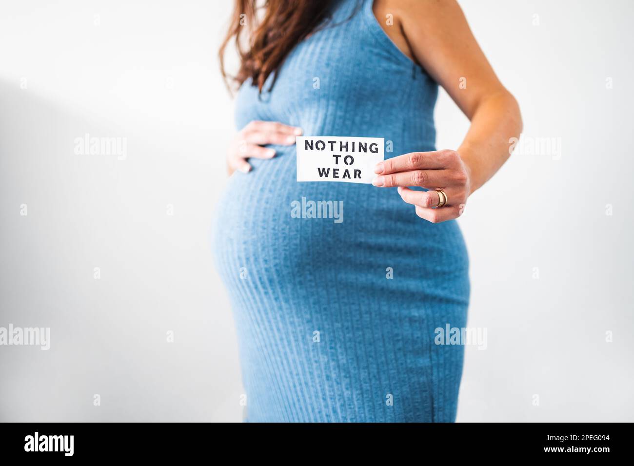 No hay nada que llevar signo sostenido por la mujer embarazada en el último  mes de embarazo con vestido azul elástico que muestra su bulto, ropa de  maternidad e inclusivo Fotografía de