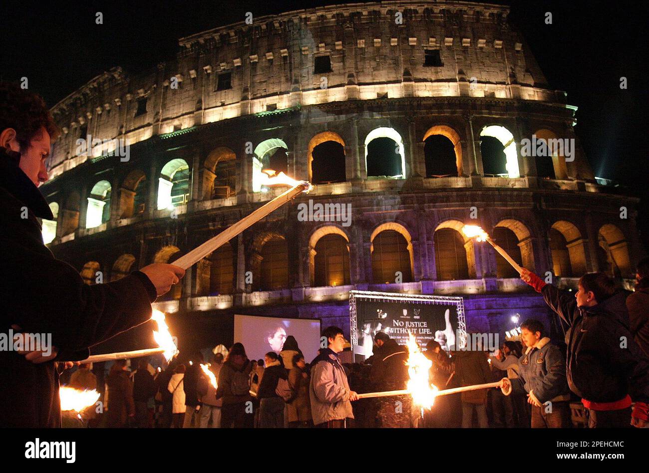 Demonstrators hold torches as they gather in front of Rome's Colosseum