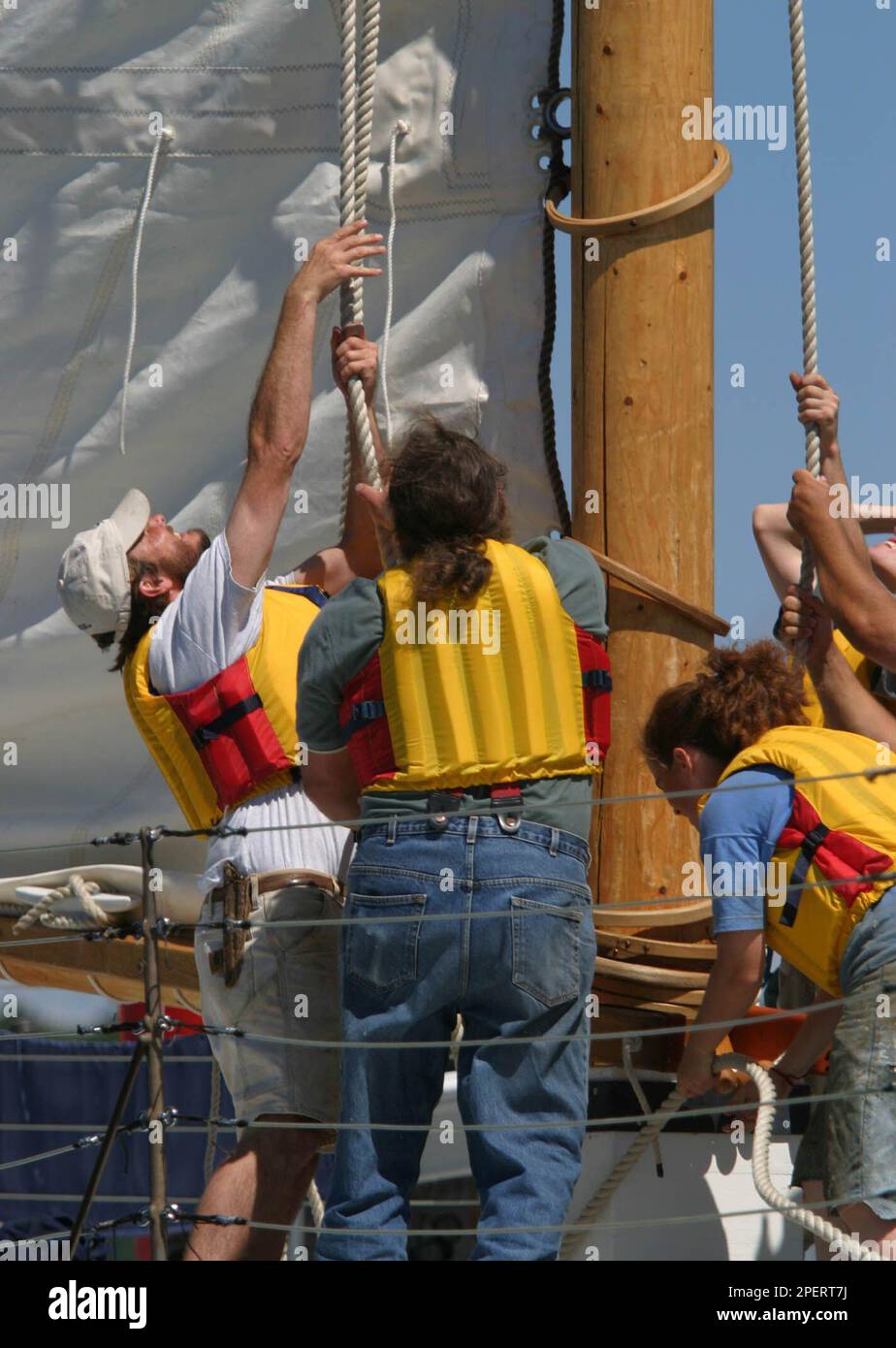 Crew members hoist the mainsail aboard the replica 1862class sailing