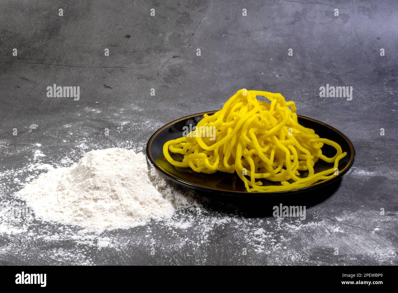 Vista lateral de fideos amarillos por huevos orgánicos y harina de todo propósito, alimentos frescos crudos caseros orientales asiáticos, fideos de huevo chinos Foto de stock