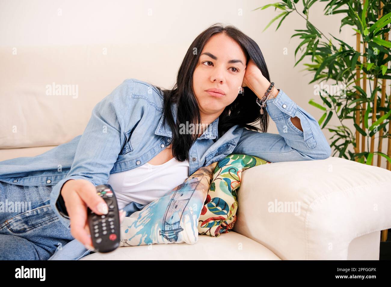 Mujer aburrida y desenganchada, buscando algo para captar su atención en la televisión en casa Foto de stock