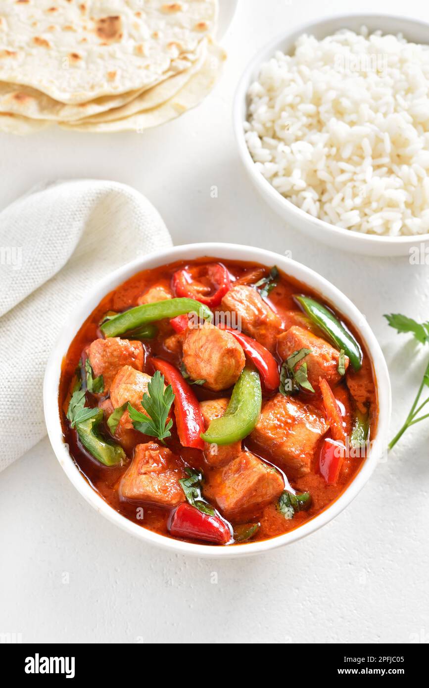 Curry de pollo rojo estilo tailandés con verduras en tazón sobre fondo de piedra blanca. Foto de stock