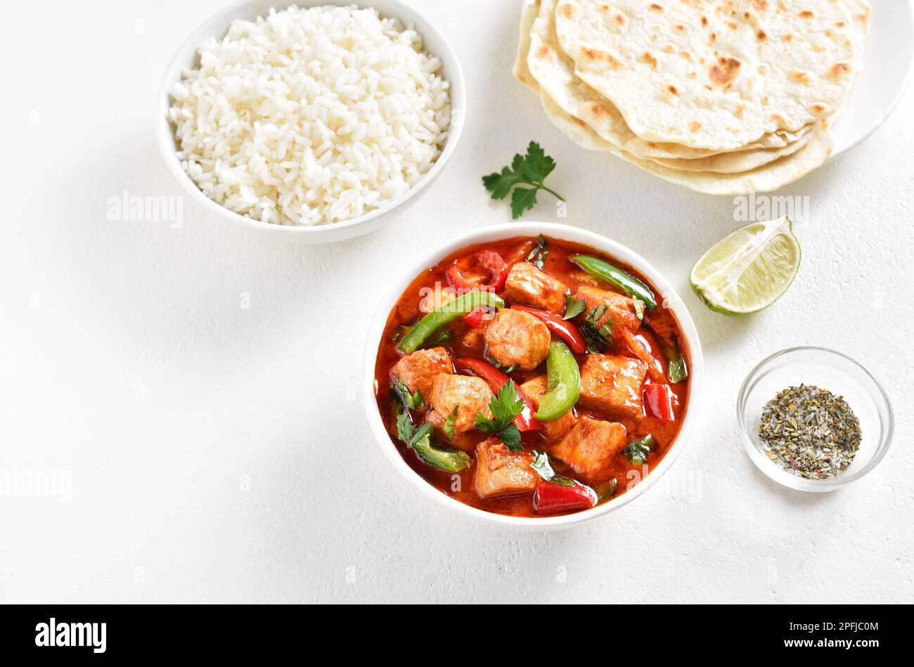 Curry de pollo rojo estilo tailandés con verduras en tazón sobre fondo blanco con espacio de texto libre. Foto de stock