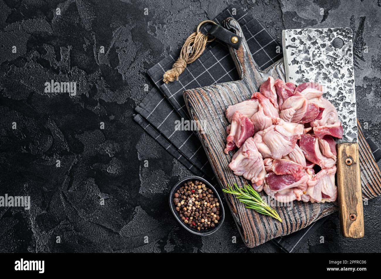 Estómagos de pollo crudo, giblets gizzards en una carnicería con cuchilla de carne. Fondo negro