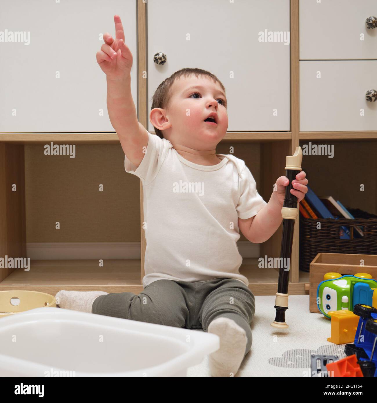 Bebé pequeño toca la flauta sentado en el suelo en la habitación de los  niños. Niño niño tocando instrumentos musicales. Niño de un año y ocho  meses Fotografía de stock - Alamy