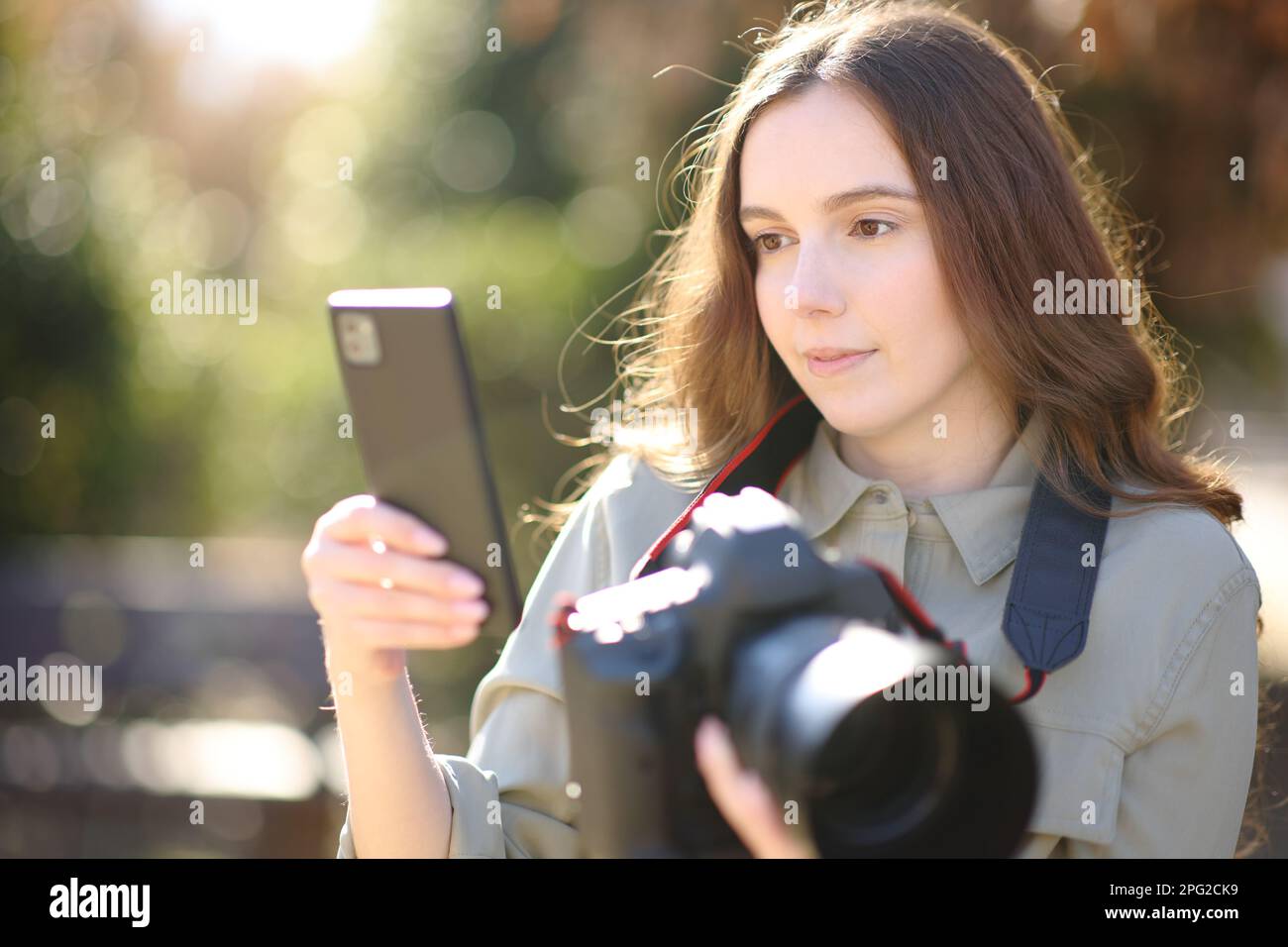 Fotógrafo emparejando aplicación de teléfono inteligente con cámara profesional dslr al aire libre Foto de stock