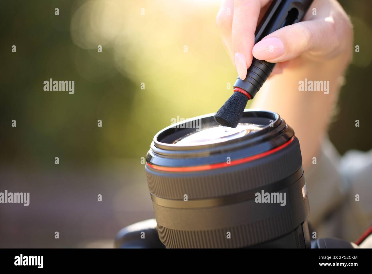 Primer plano retrato de un fotógrafo que limpia la lente de la cámara con el cepillo al aire libre Foto de stock