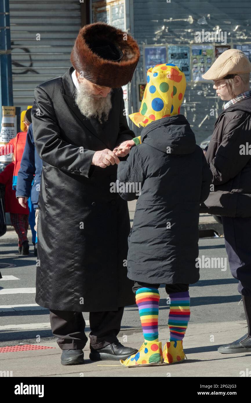 Un hombre judío jasídico mayor cumple con su obligación de Purim de dar caridad. En Brooklyn, Nueva York. Foto de stock