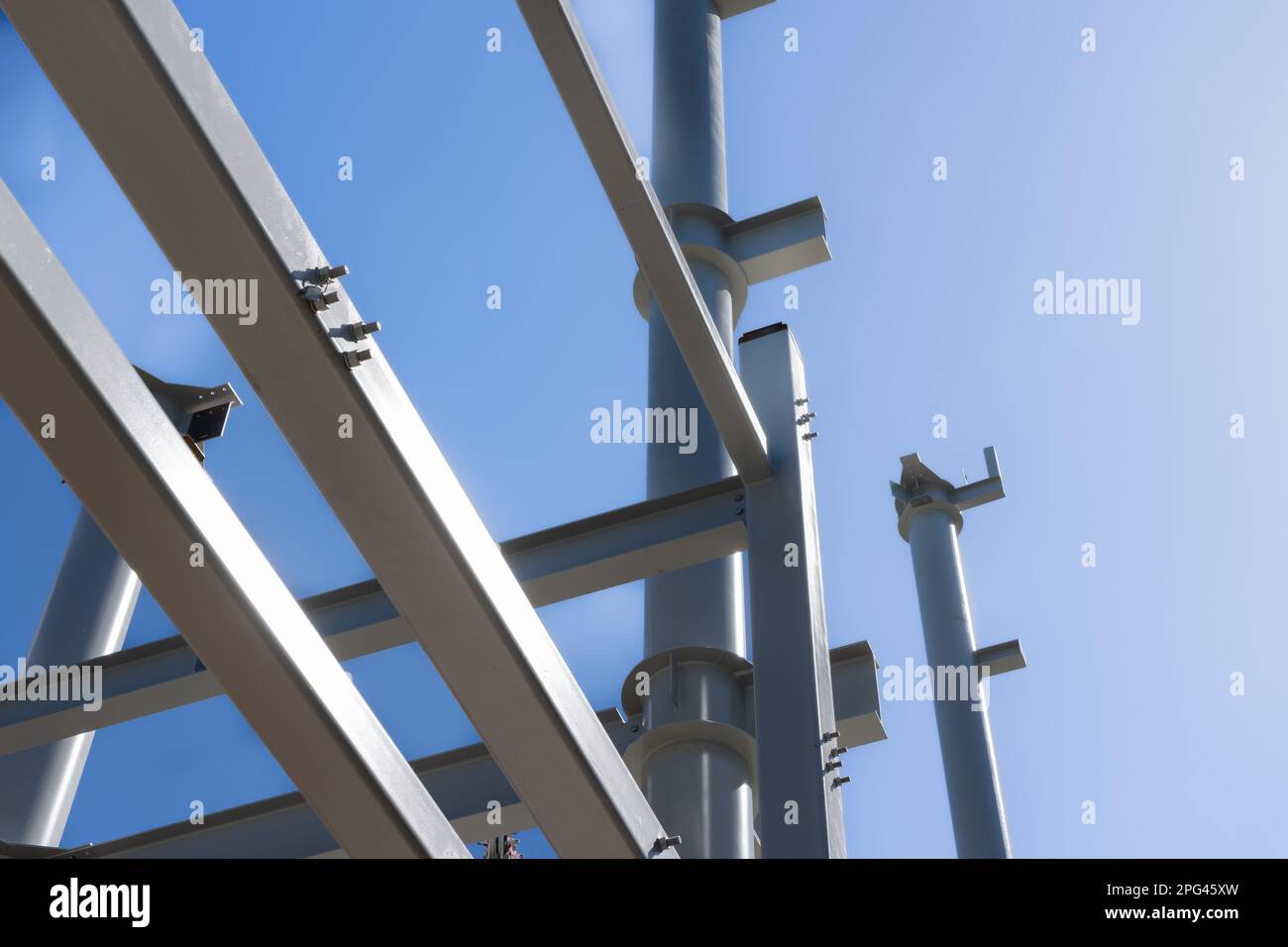 Cielo azul sobre vigas de acero estructural y postes que se erigen en la construcción del edificio. Foto de stock