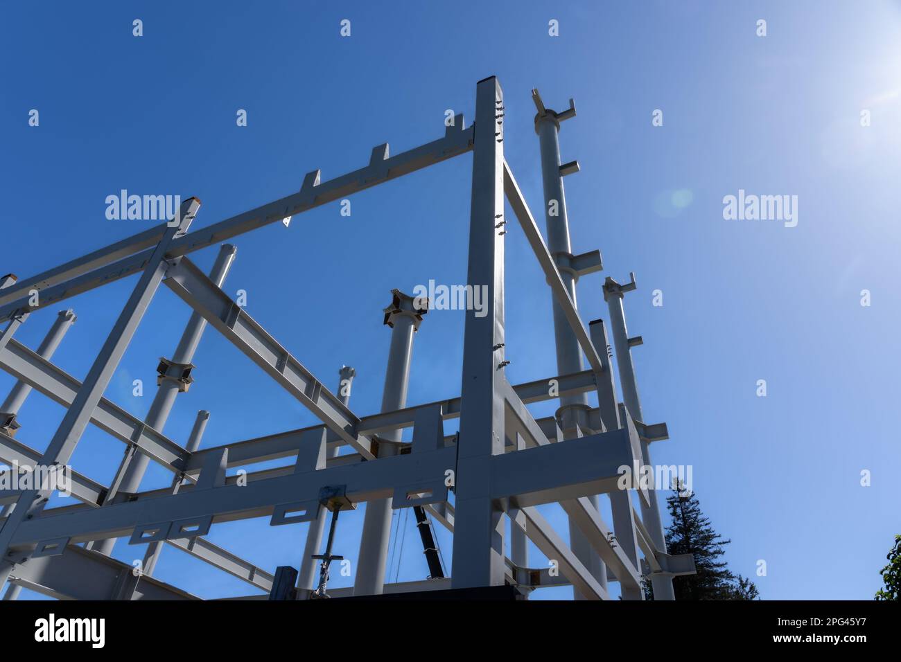 Cielo azul sobre vigas de acero estructural y postes que se erigen en la construcción del edificio. Foto de stock