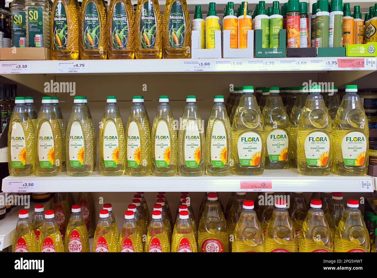Estante del supermercado lleno de aceites refrescantes incluyendo aceite de oliva virgen Foto de stock