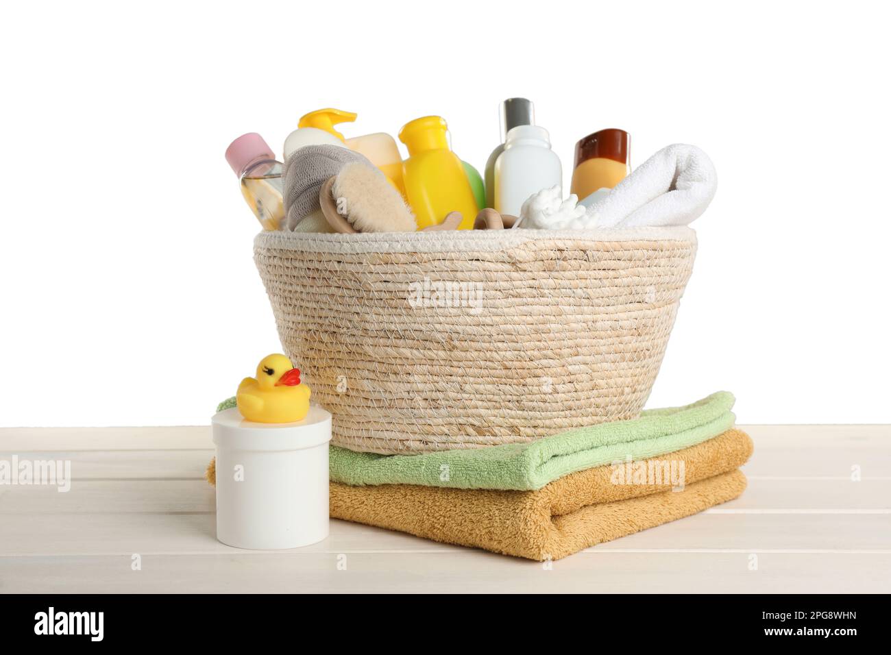Cesta de mimbre llena de diferentes productos cosméticos para bebés,  accesorios de baño y juguetes sobre mesa de madera contra fondo blanco  Fotografía de stock - Alamy