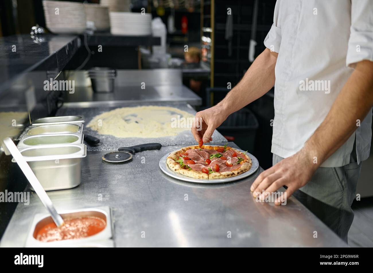 Pizzaiolo haciendo pizza en la cocina con enfoque de primer plano en la mano Foto de stock