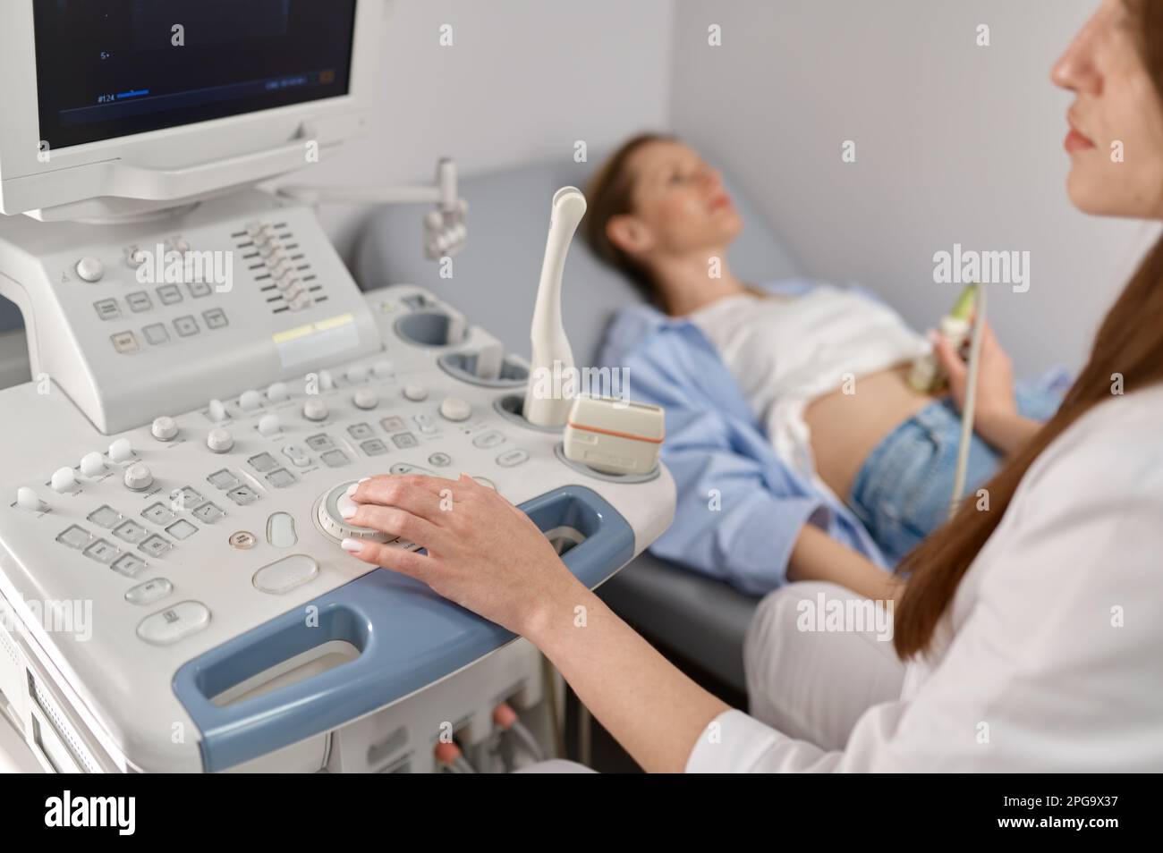 Médico de enfoque selectivo haciendo ultrasonido del feto a la mujer embarazada Foto de stock