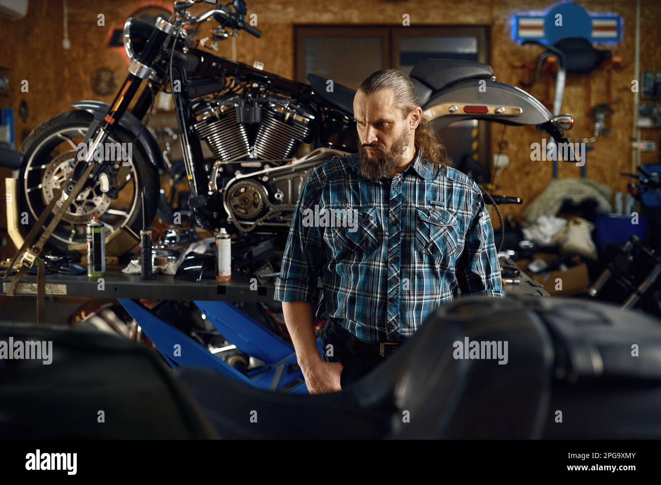 Retrato del ciclista brutal barbudo en la motocicleta en el taller de garaje Foto de stock